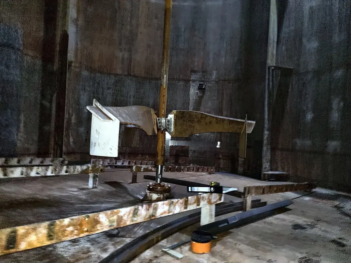 Lower agitator impeller bolted to the shaft inside a storage tank, with the bearing on the floor below it