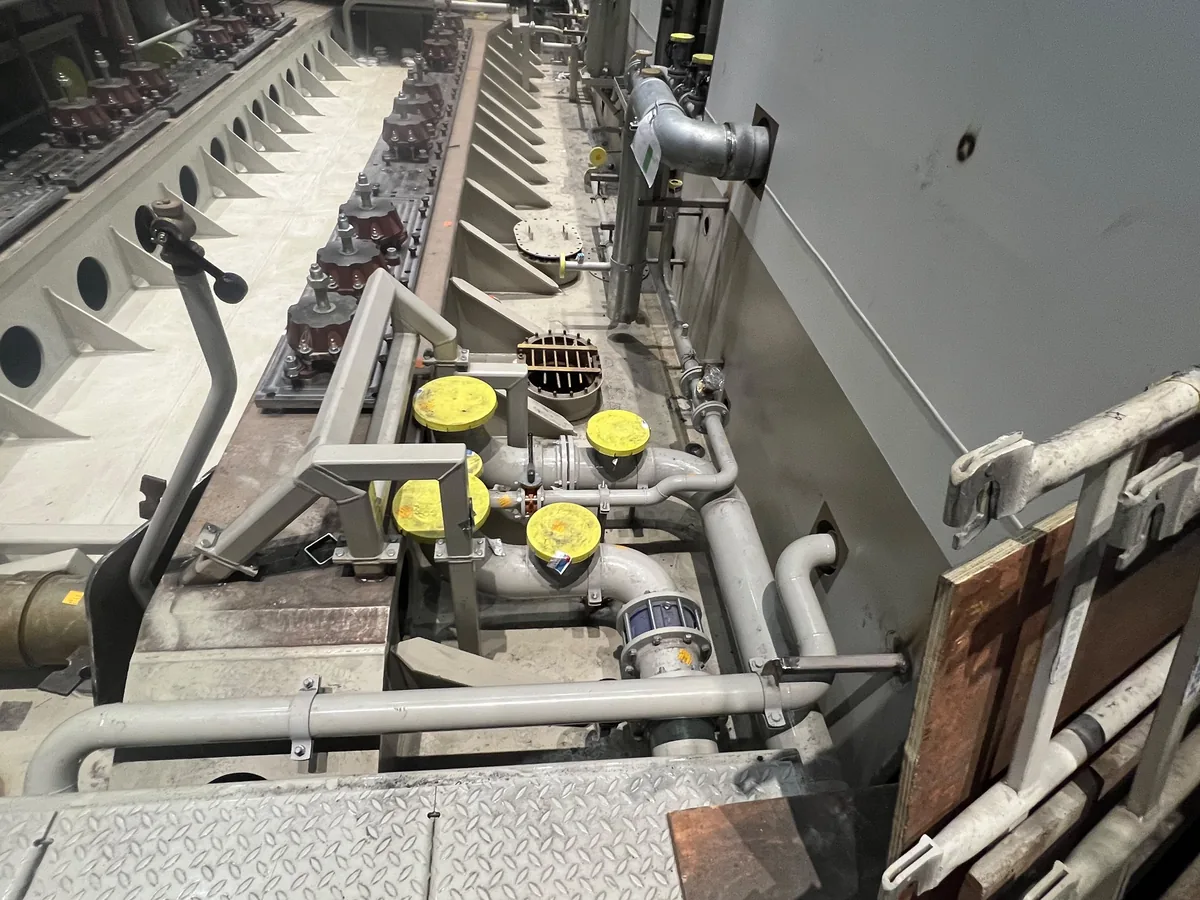A row of resilient mounts along the machined seating, with the first pipe runs and capped flanges laid in beside them