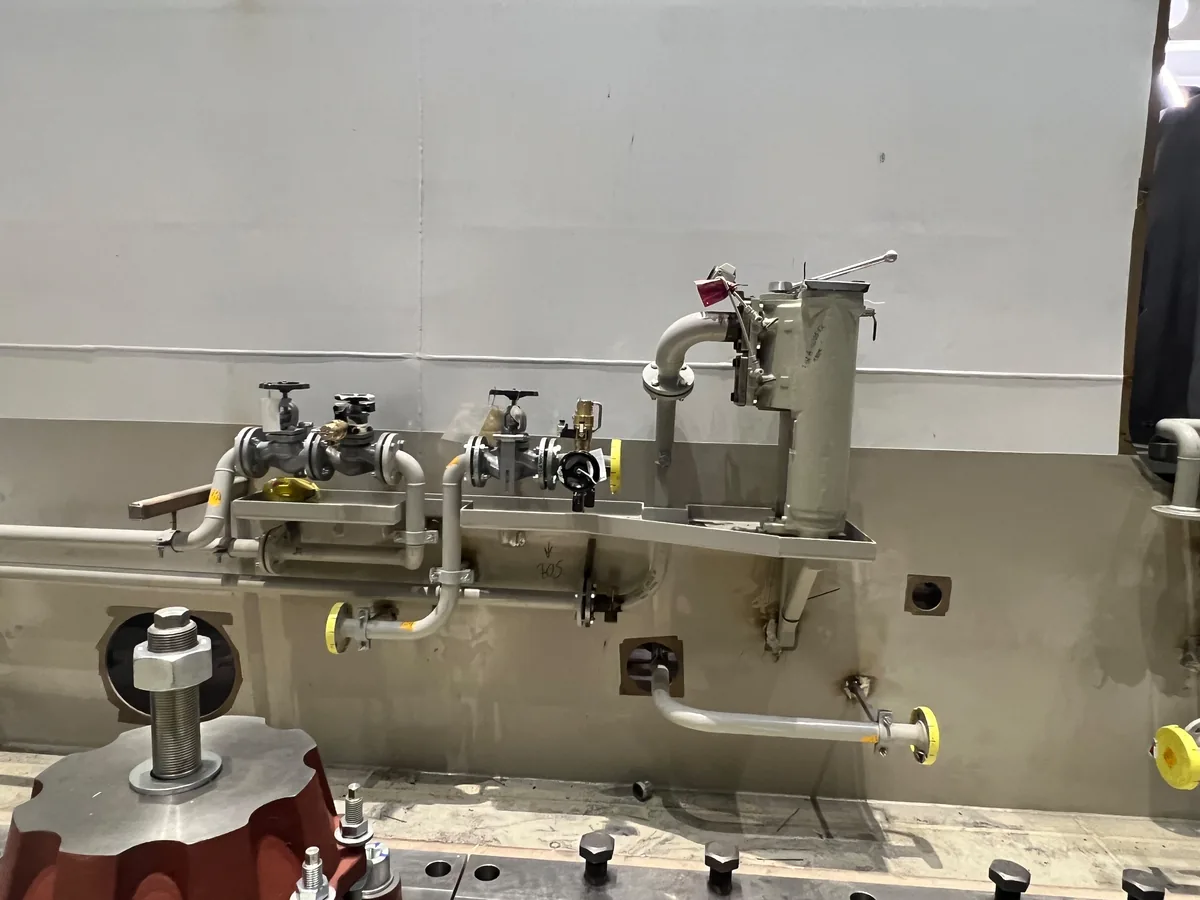 Valve and strainer group made up on a frame against an engine room bulkhead, with globe valves, a basket strainer and capped branches