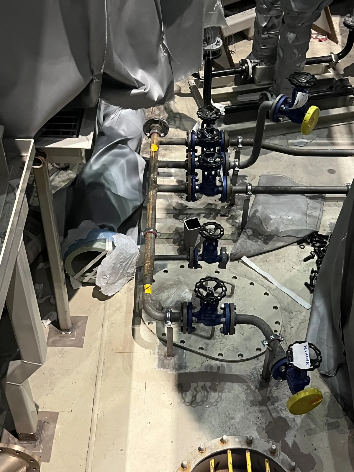 Valve group set out around a bolted tank access cover, with the covers left clear and every open end capped