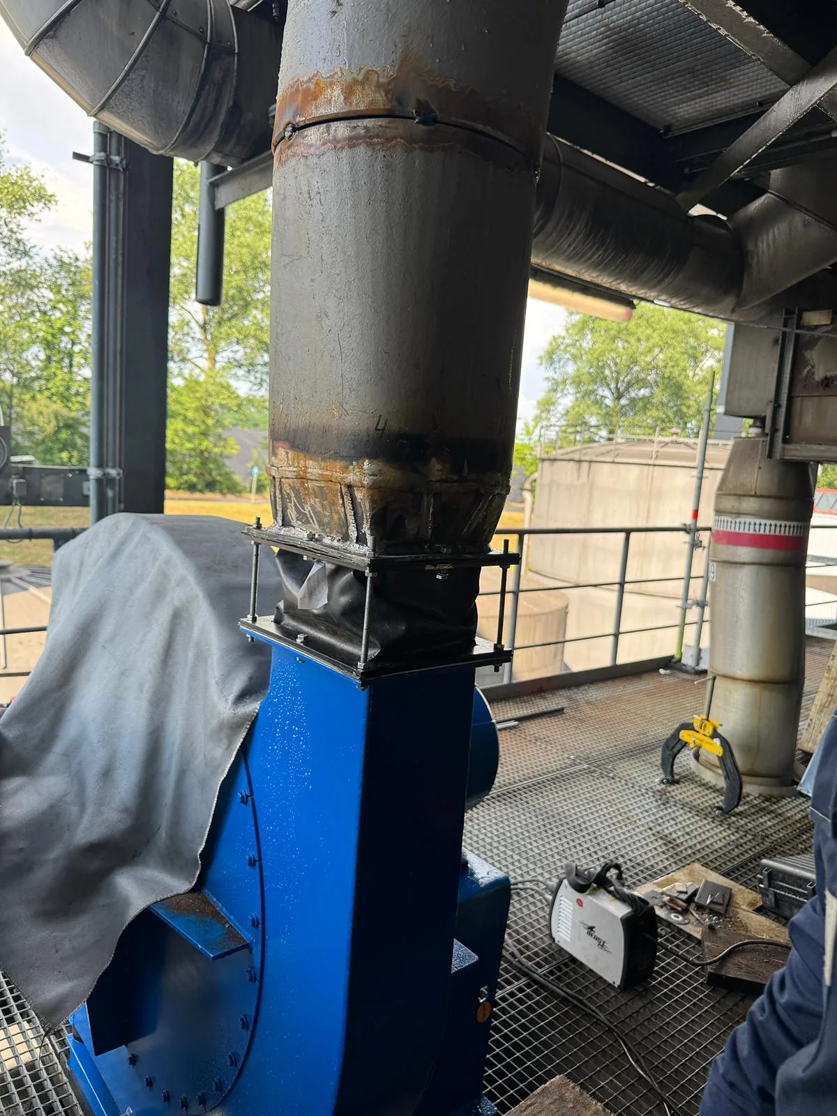 Fabric expansion joint with tie rods bolted between the fan outlet and the adapted exhaust duct above it