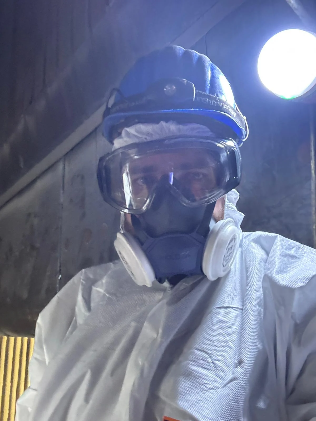 Worker in a hard hat, goggles and P3 respirator inside the cold furnace of a waste-to-energy plant