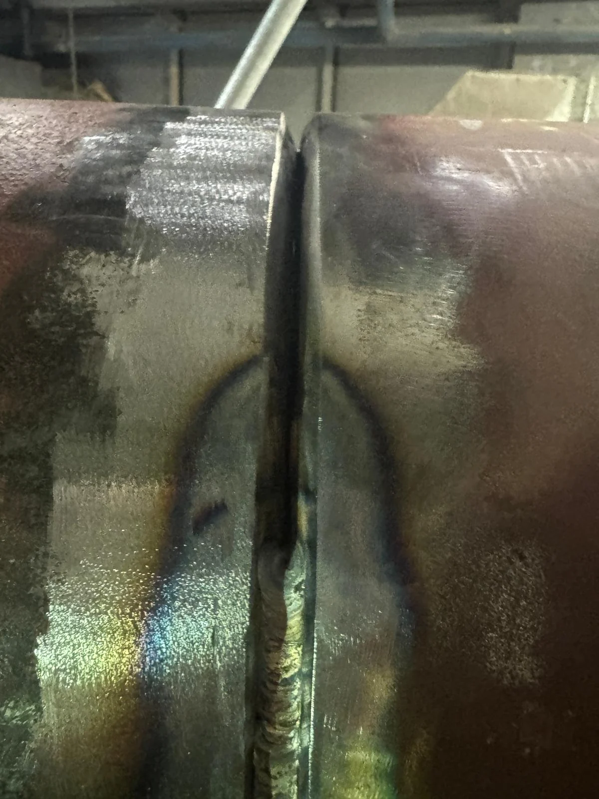 Close-up of a pipe butt joint with an even root gap and the root run part way round
