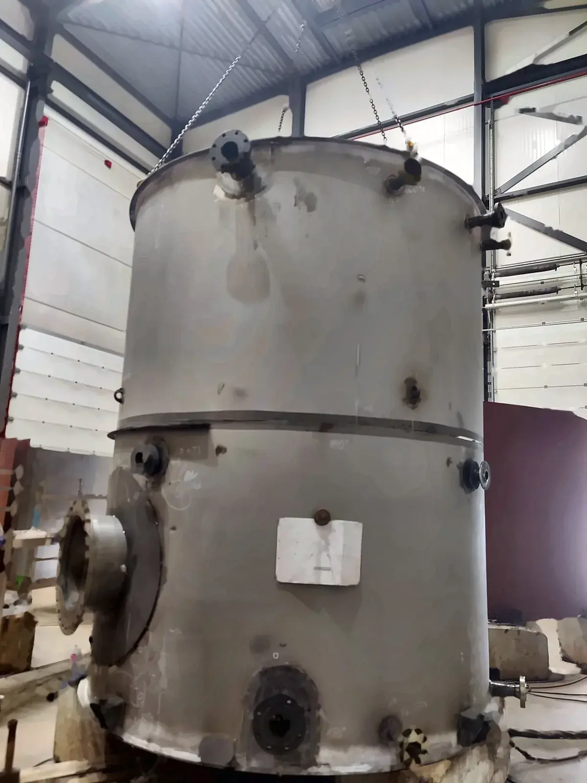 Assembled vessel standing on blocks, with nozzles, a side manway and a drawing taped to the shell