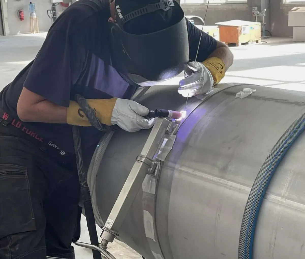 TIG welder working on a large-diameter stainless pipe