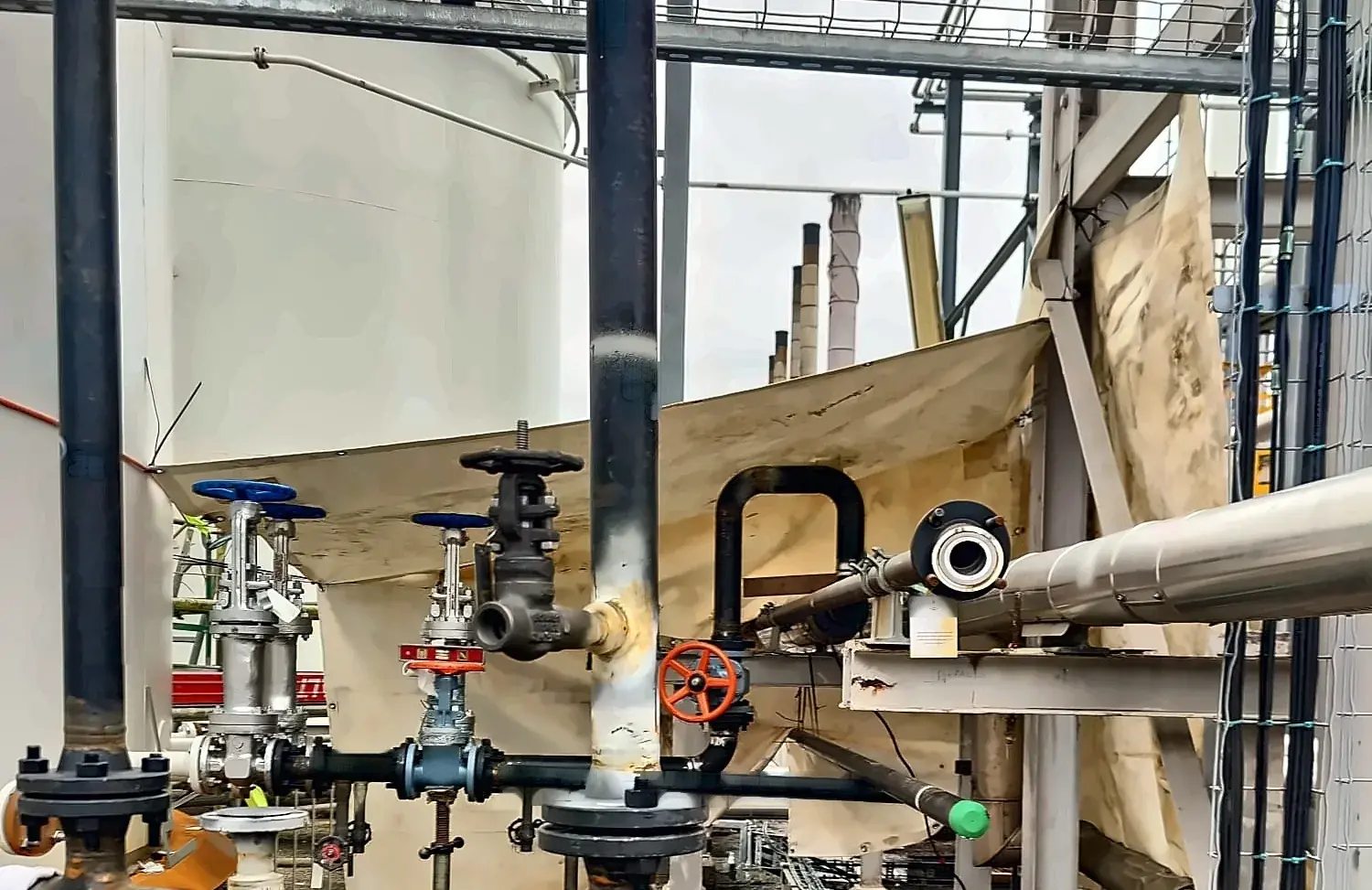 Tie-in piping and valve station at a tank farm, with gate and globe valves set on stands and the run tying into the existing rack